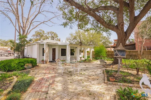 a front view of a house with a garden and trees