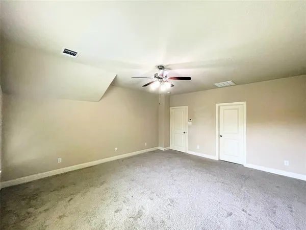 a view of an empty room with wooden floor kitchen view and a window