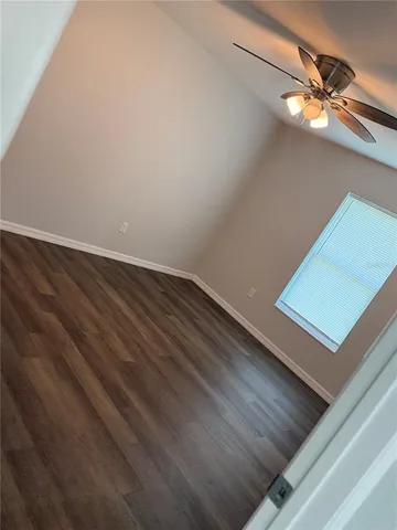 a view of a room with a ceiling fan and wooden floor