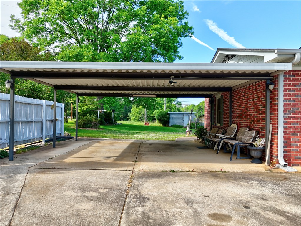 307 Calhoun Road Belton, SC 29627 - Photo 6 of 30 A spacious carport offers convenient parking adjacent to a brick-clad home with a generous backyard.