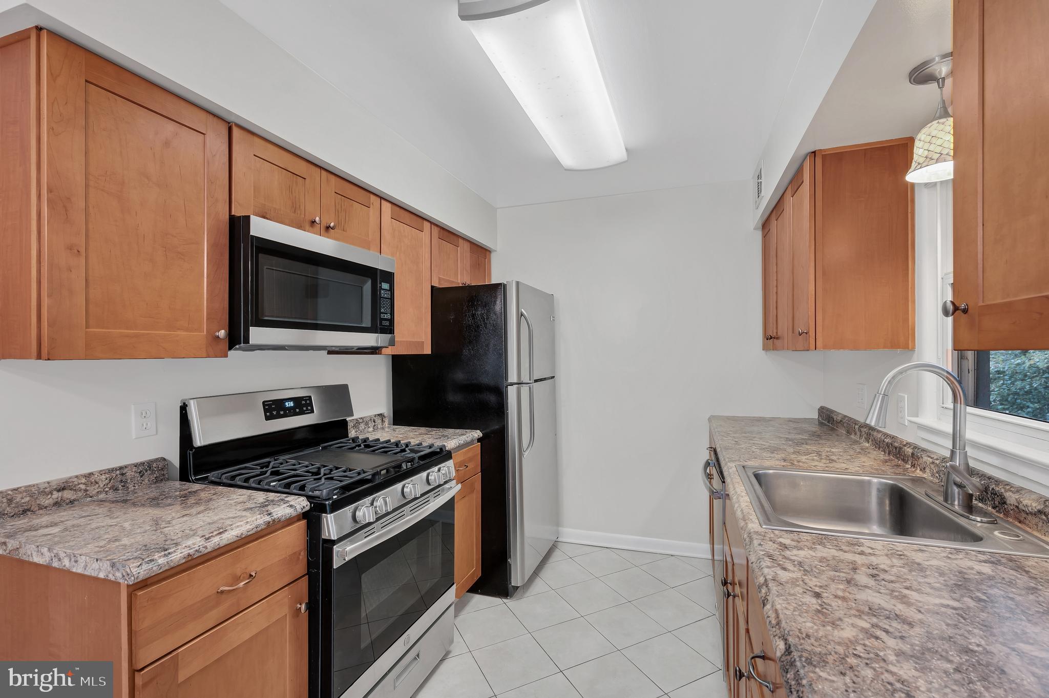 12002 Cook Court Silver Spring, MD 20902 - Photo 10 of 31 a kitchen with stainless steel appliances granite countertop a sink stove microwave and refrigerator