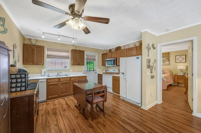 a kitchen with stainless steel appliances granite countertop a refrigerator a stove a sink dishwasher and a dining table with wooden floor