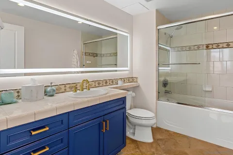 a bathroom with a granite countertop sink a toilet and shower