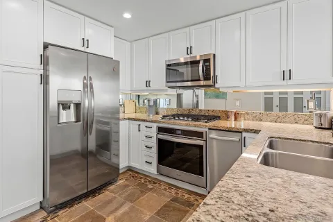 a kitchen with stainless steel appliances granite countertop a stove a refrigerator and a microwave