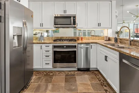 a kitchen with stainless steel appliances granite countertop a stove a sink and a refrigerator
