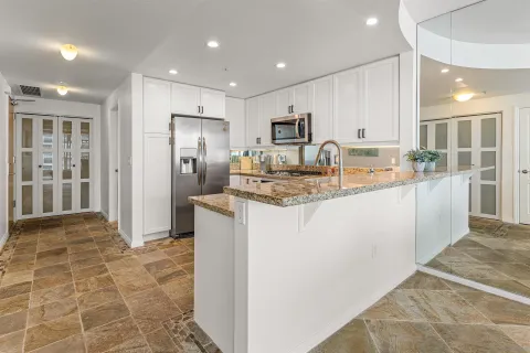 a kitchen with kitchen island granite countertop a stove refrigerator and cabinets