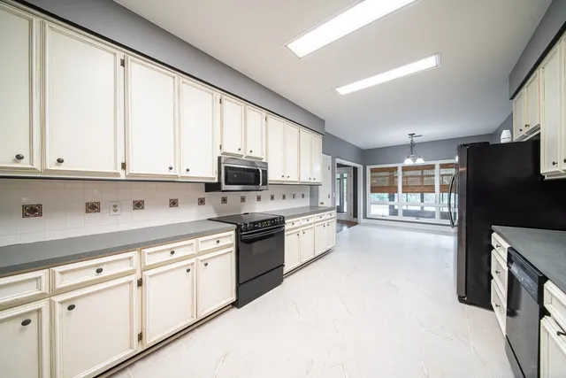 a kitchen with stainless steel appliances granite countertop a refrigerator a sink dishwasher a stove and white cabinets