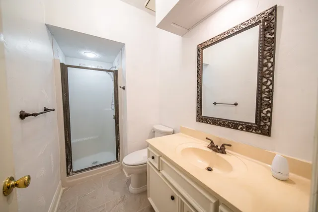 a bathroom with a granite countertop sink toilet and shower