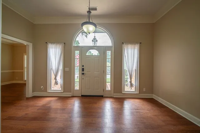 an empty room with wooden floor mirror and windows