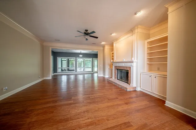a view of an empty room with window and wooden floor