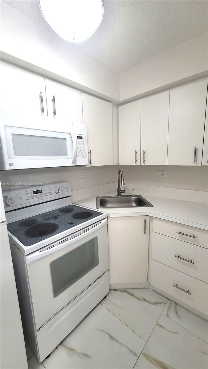 5201 Northwest 7th Street, Unit 106 Miami, FL 33126 - Photo 5 of 20 a kitchen with white cabinets and white appliances