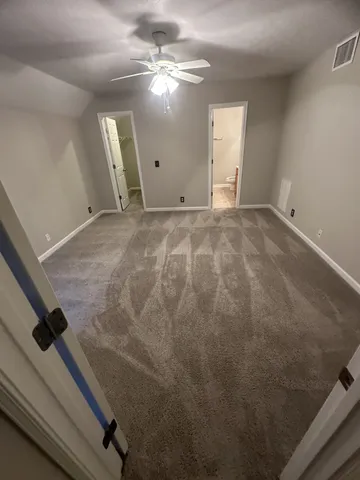 an empty room with windows and fan