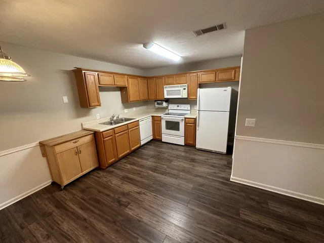 a kitchen with a white cabinets a sink and wooden floor