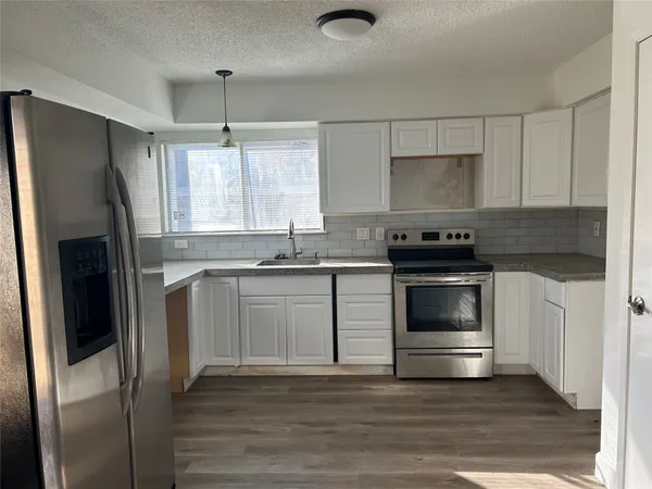 an empty room with wooden floor cabinet and windows