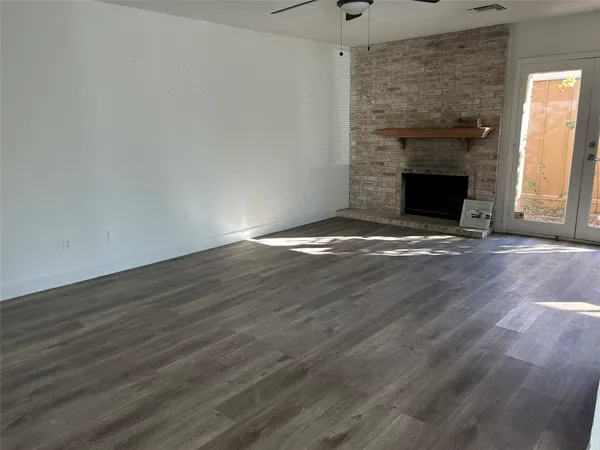 a view of an empty room with wooden floor and a fireplace