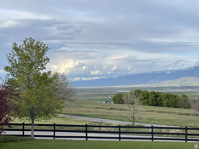 7030 West 2100 North Mendon, UT 84325 - Photo 13 of 67 Expansive landscape with distant snow-capped mountains and a black rail fence