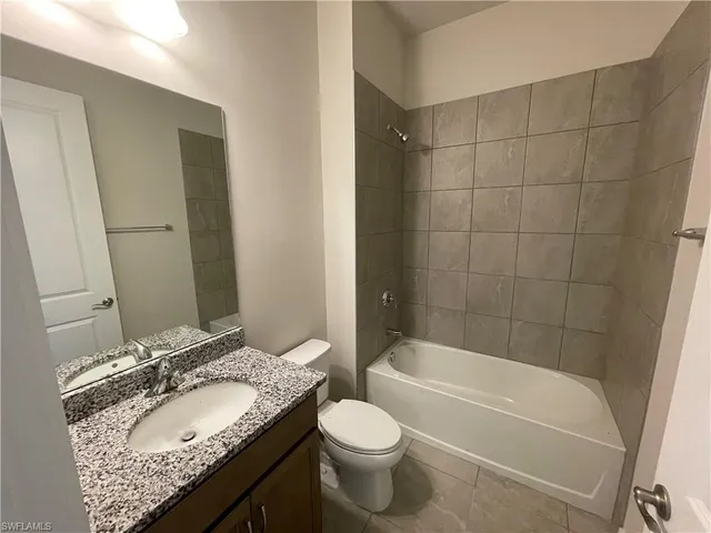 a bathroom with a granite countertop sink toilet mirror and bathtub