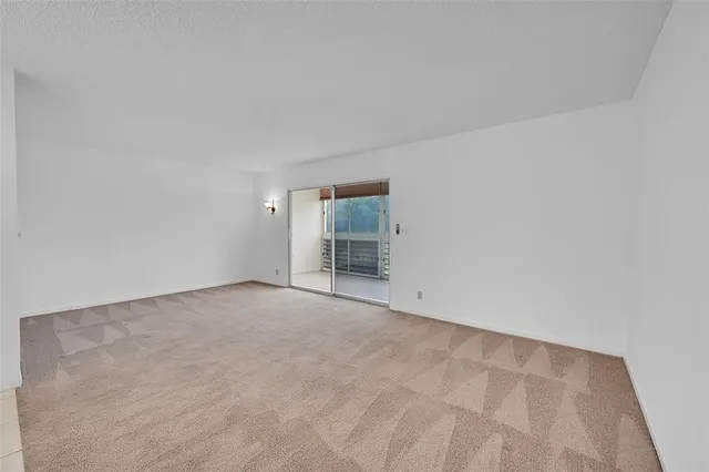 an empty room with a chandelier fan and windows