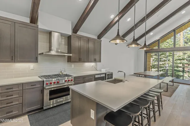 a kitchen with stainless steel appliances a stove a sink a cabinets and chairs