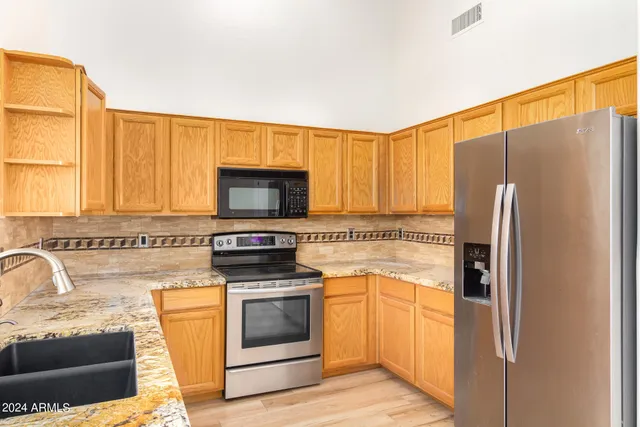 a kitchen with granite countertop a refrigerator stove and microwave