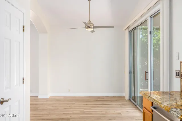 an empty room with wooden floor fan and windows