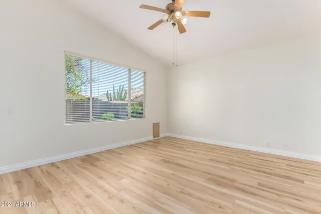 an empty room with wooden floor fan and windows