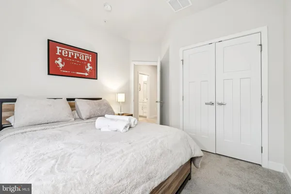 a spacious bedroom with a bed a dresser and a large window