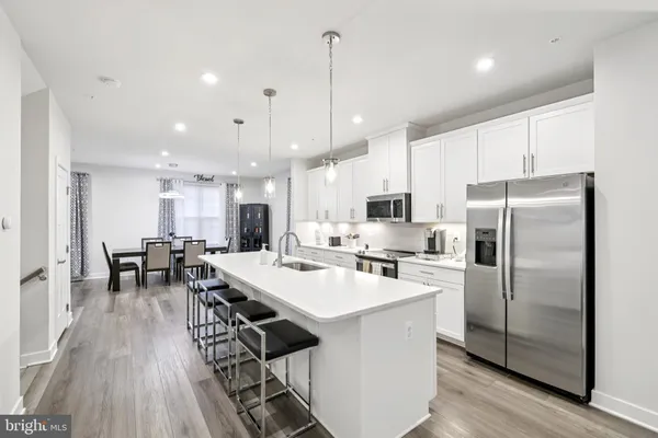 a kitchen with stainless steel appliances a dining table chairs stove refrigerator and wooden floor