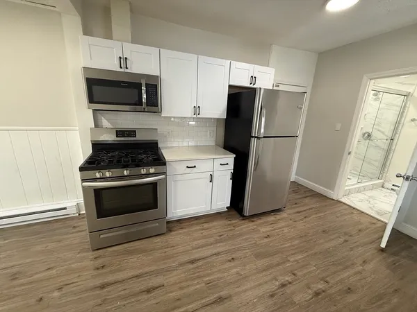 a kitchen with a refrigerator stove and wooden floor