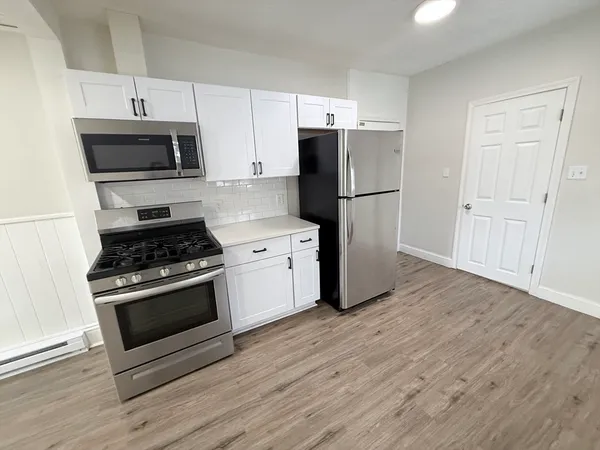a kitchen with stainless steel appliances a stove a microwave and a hard wood floors