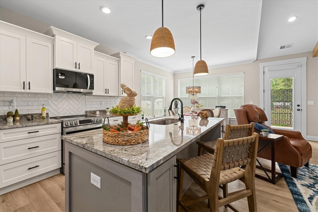 6834 Midway Road Pelzer, SC 29669 - Photo 19 of 50 This kitchen features a beautiful island with granite counters, modern appliances, and stylish lighting.