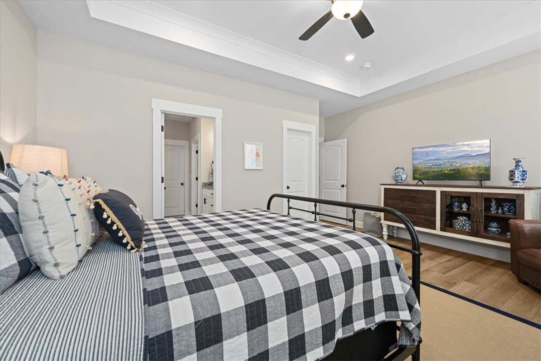 6834 Midway Road Pelzer, SC 29669 - Photo 23 of 50 This spacious bedroom features a ceiling fan, recessed lighting, and elegant tray ceilings.