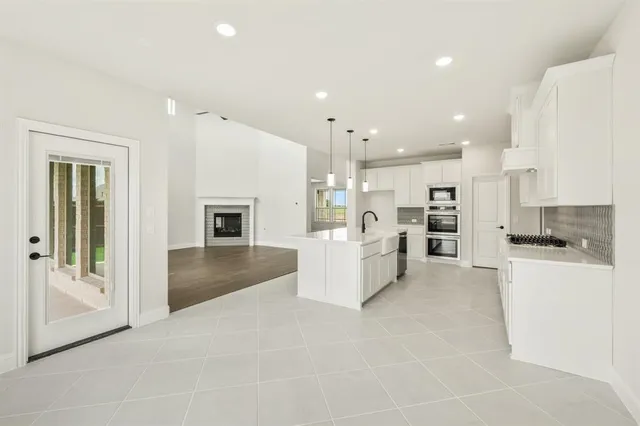 a large white kitchen with stainless steel appliances kitchen island a large counter top and a stove top oven