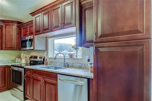 a kitchen with stainless steel appliances granite countertop a stove a sink and a refrigerator