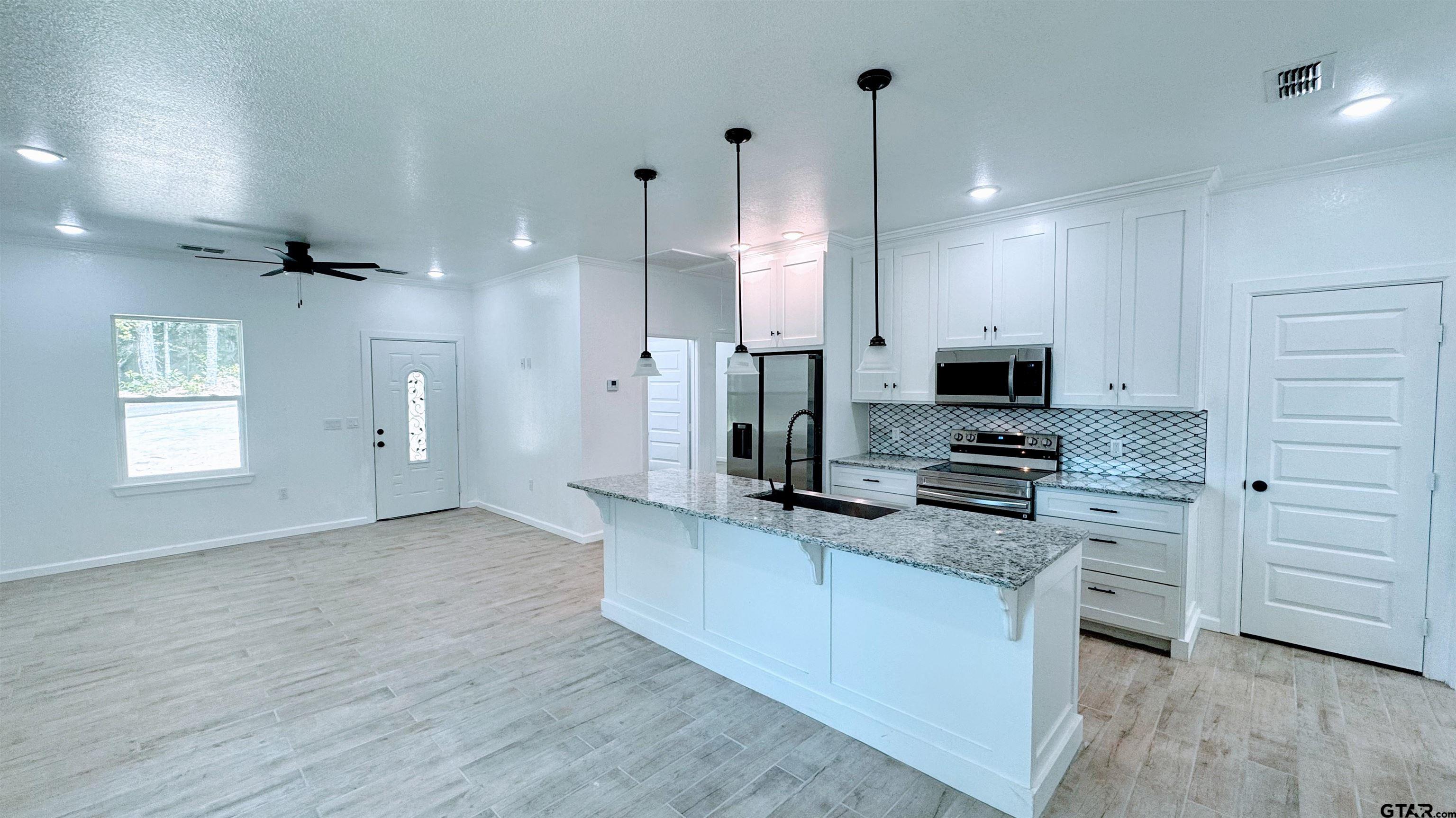 20428 High Point Drive Flint, TX 75762 - Photo 2 of 18 a kitchen with stainless steel appliances a stove a sink cabinets and a wooden floor
