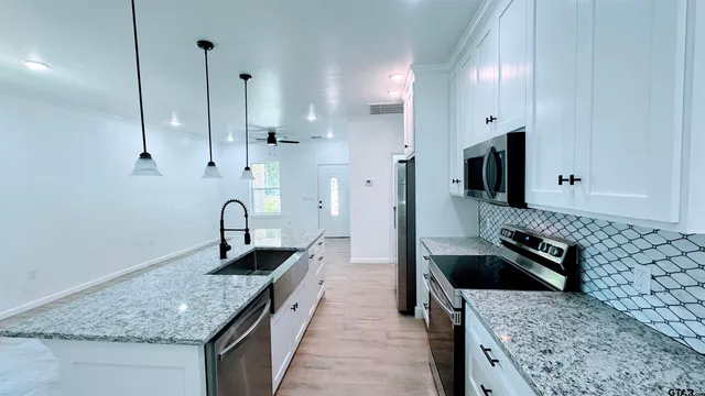 a kitchen with granite countertop sink stove and cabinets