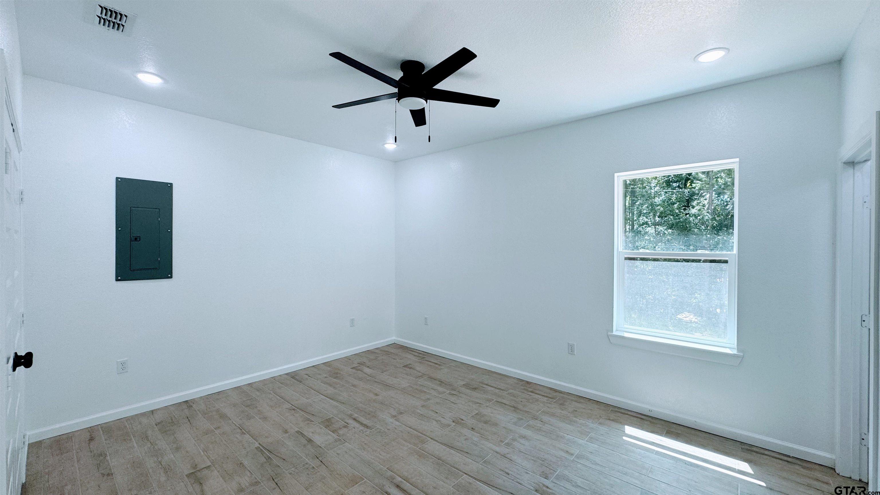 20428 High Point Drive Flint, TX 75762 - Photo 8 of 18 an empty room with wooden floor ceiling fan and windows