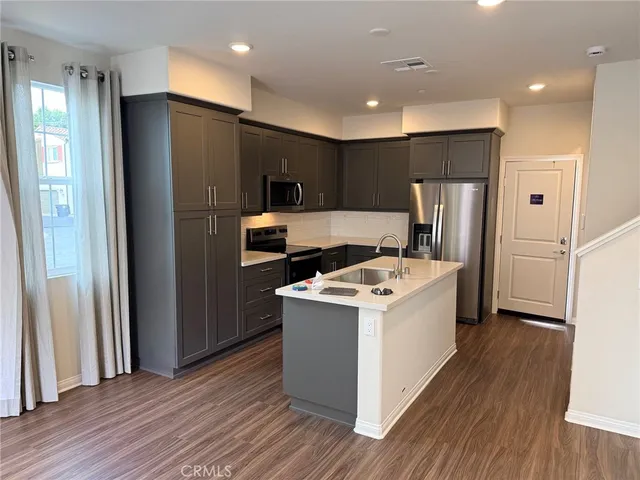a view of kitchen with refrigerator stove and wooden floor