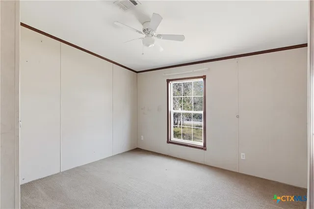 an empty room with windows and fan