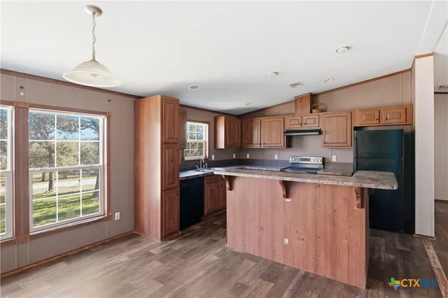 a large kitchen with stainless steel appliances granite countertop a sink a stove a refrigerator a center island and a window