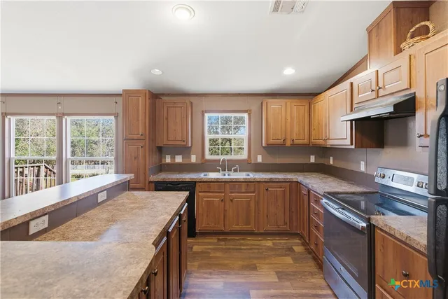 a kitchen with stainless steel appliances granite countertop wooden cabinets a sink and a stove