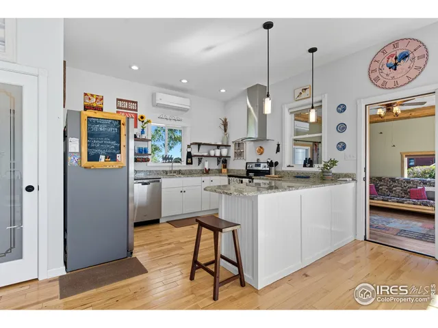a kitchen with stainless steel appliances granite countertop a sink a stove a refrigerator and white cabinets