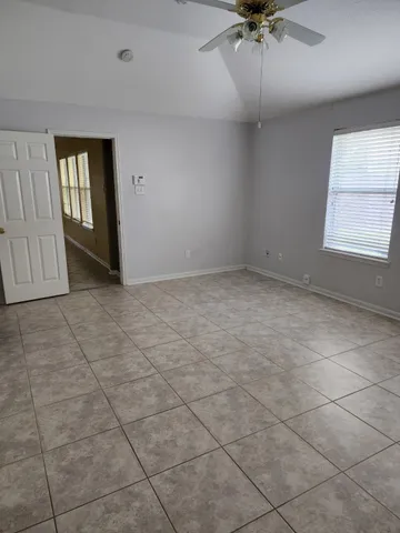 an empty room with a ceiling fan and windows