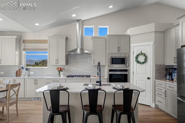 a kitchen with stainless steel appliances granite countertop a stove top oven a sink a dining table and chairs