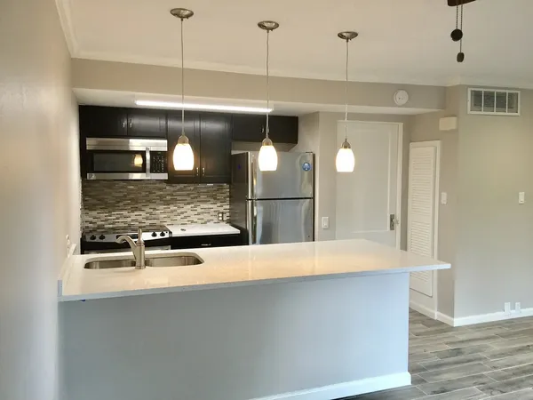 a view of a kitchen with a refrigerator a sink and wooden floor