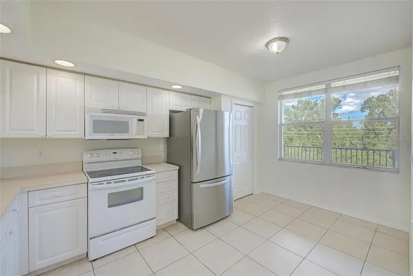 a kitchen with a stove a refrigerator and white cabinets