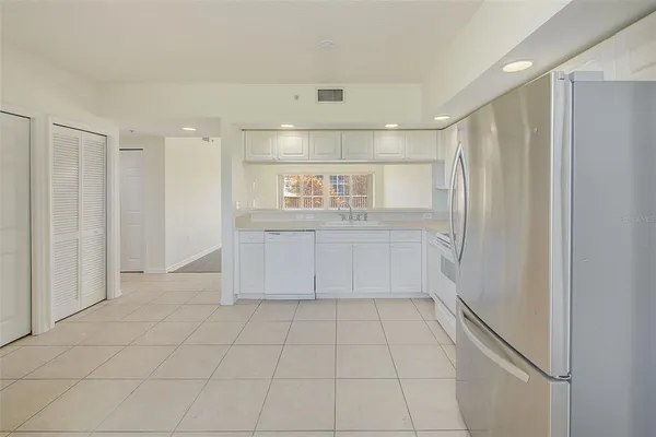 a view of a refrigerator in kitchen and white cabinets