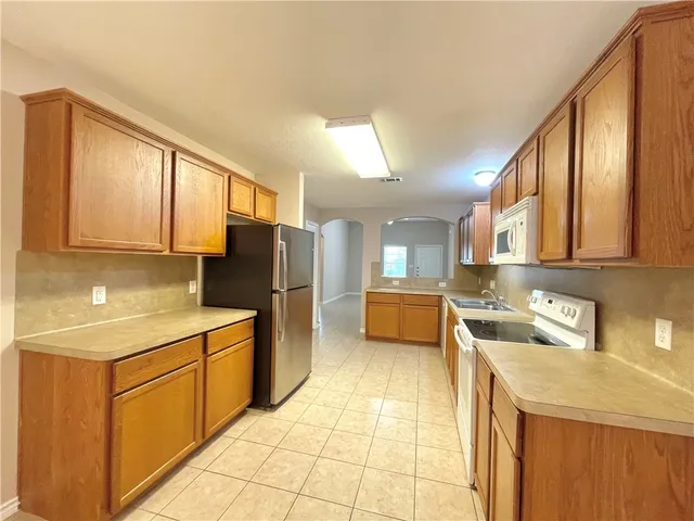 a kitchen with a sink a stove top oven and refrigerator