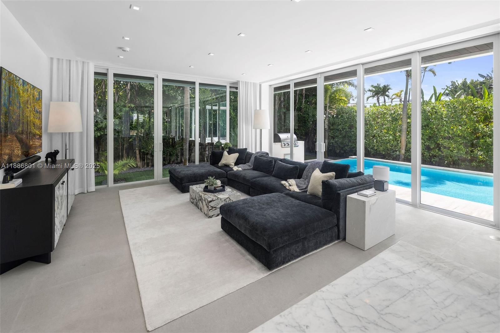 4433 North Bay Road Miami Beach, FL 33140 - Photo 38 of 71 a living room with furniture large windows and a flat screen tv