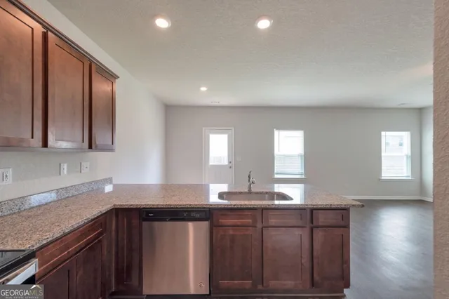 a kitchen with stainless steel appliances granite countertop a sink a stove cabinets and wooden floor